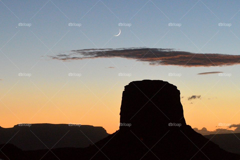 Sunset with a sliver of moon in Monument Valley, Utah.  