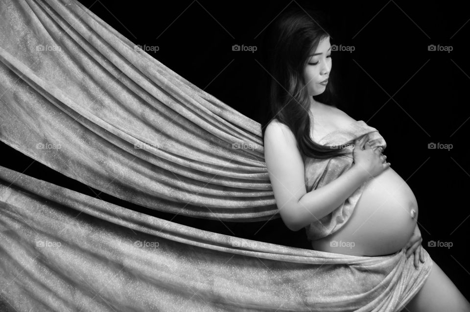 Pregnant woman covering her body with curtain