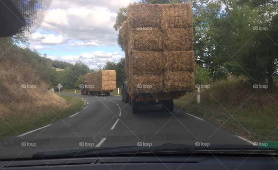Tractors carrying hay bales, France.