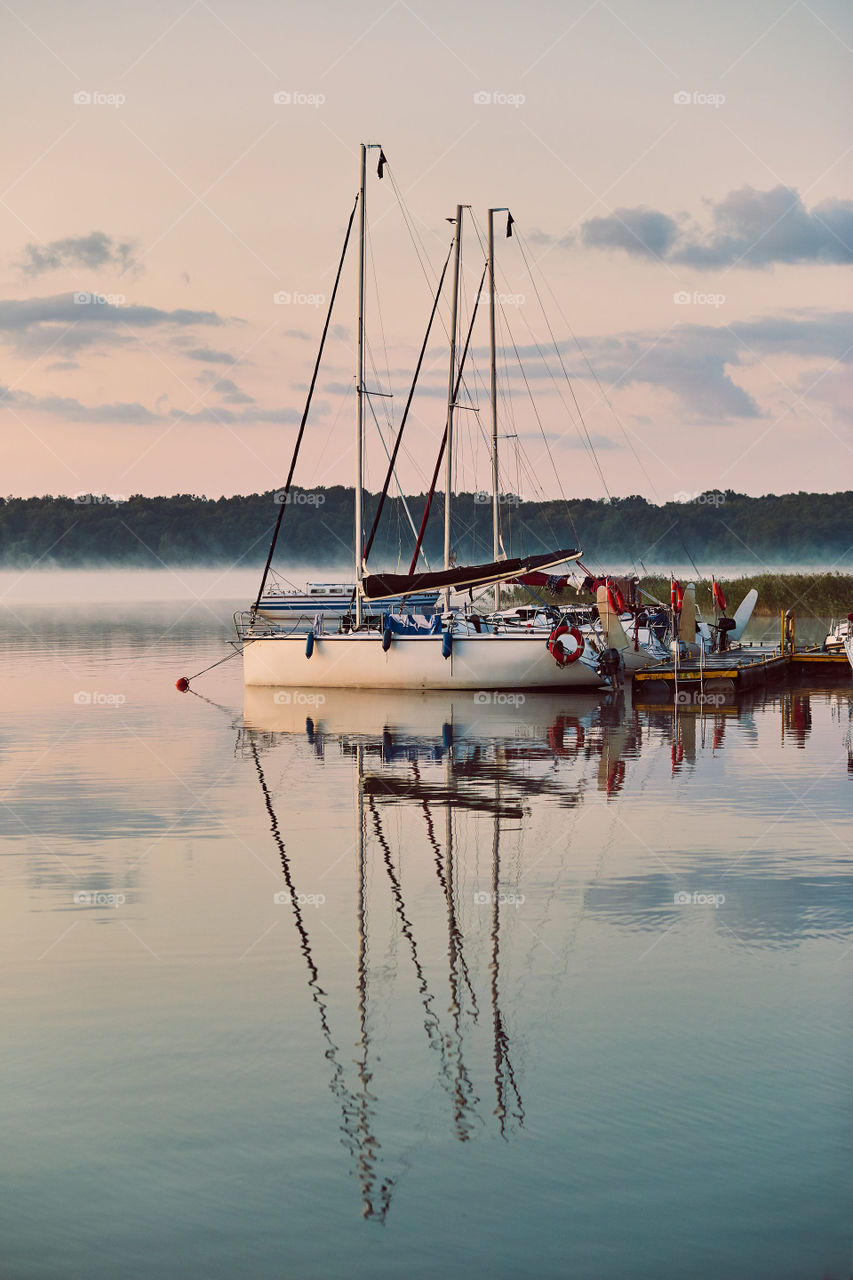 Yachts and boats moored in a harbour at sunrise. Candid people, real moments, authentic situations