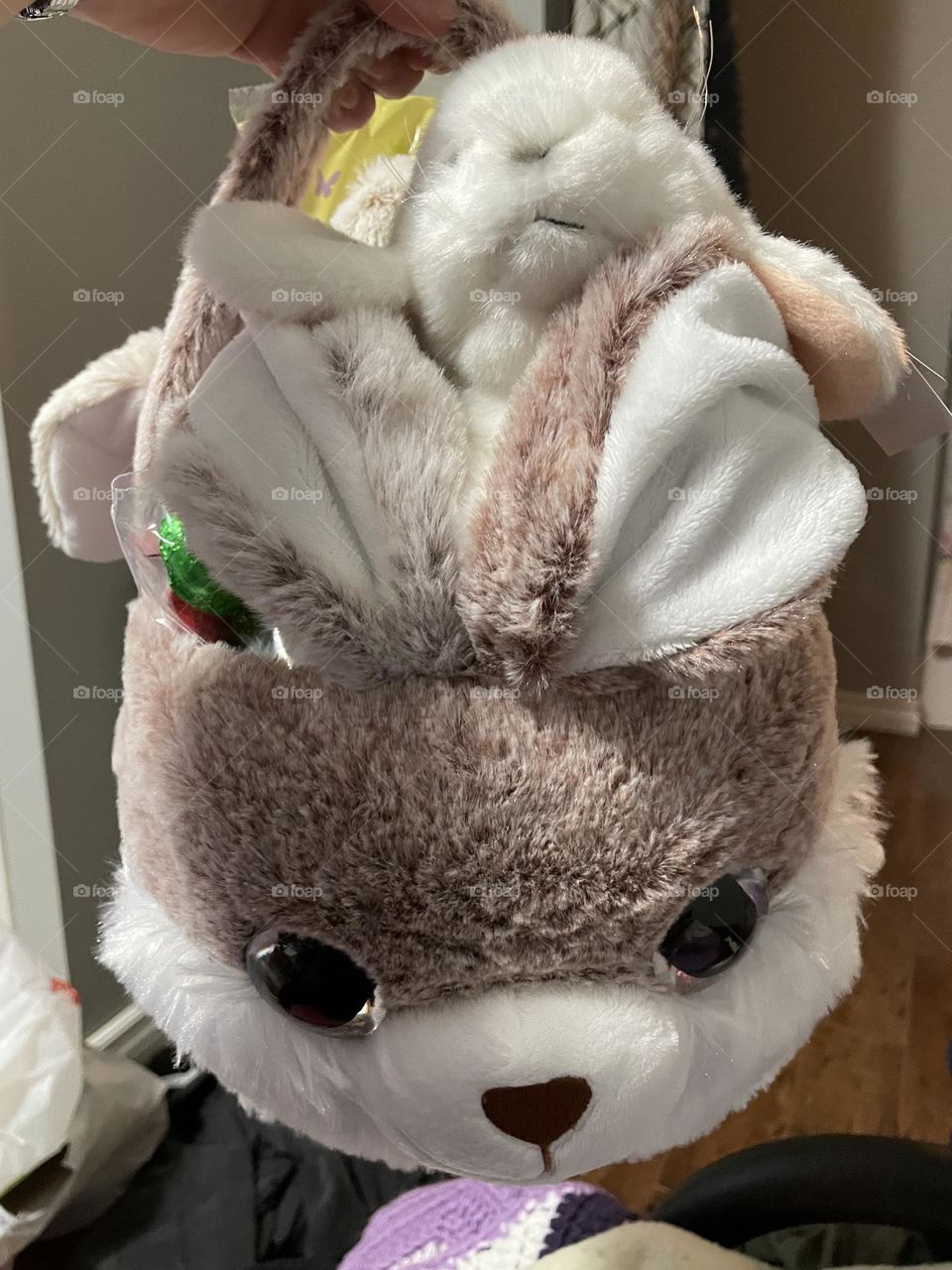 A brown and white rabbit, with a white rabbit riding on top, with a bunch of treats inside