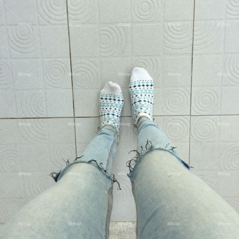 Selfie feet wearing white vintage socks on floor background, jeans and feet great for any use.