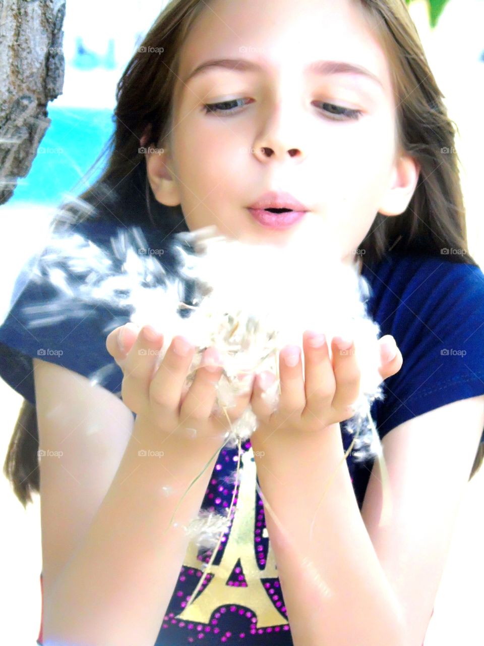 the girl blows the fluff off her palms