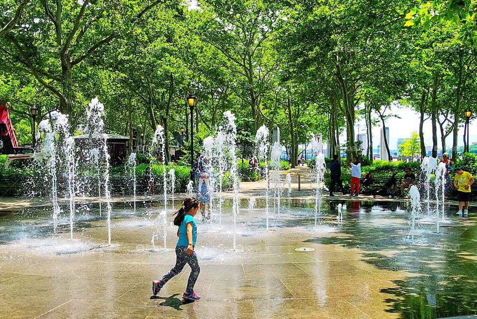 The joys of childhood as a young girl takes advantage of the water fountain at Battery Park on a steamy day in New York City! 