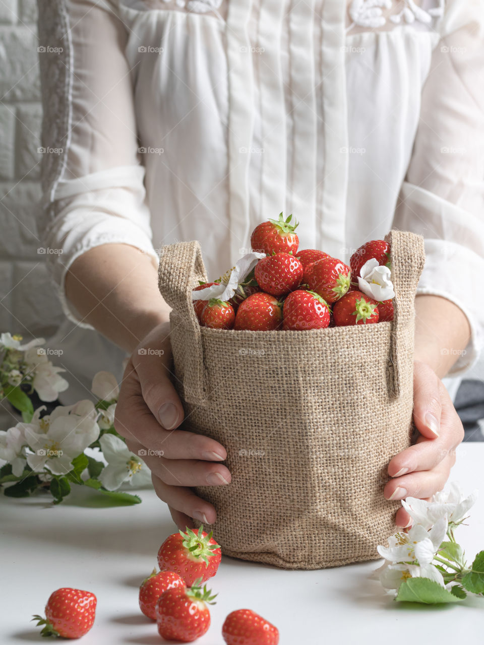 Holding a jute bag full of ripe fresh strawberries 