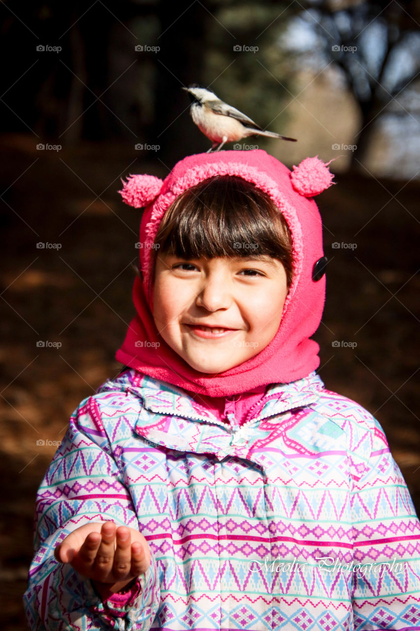 Cute smiling girl with a black-capped chikadee