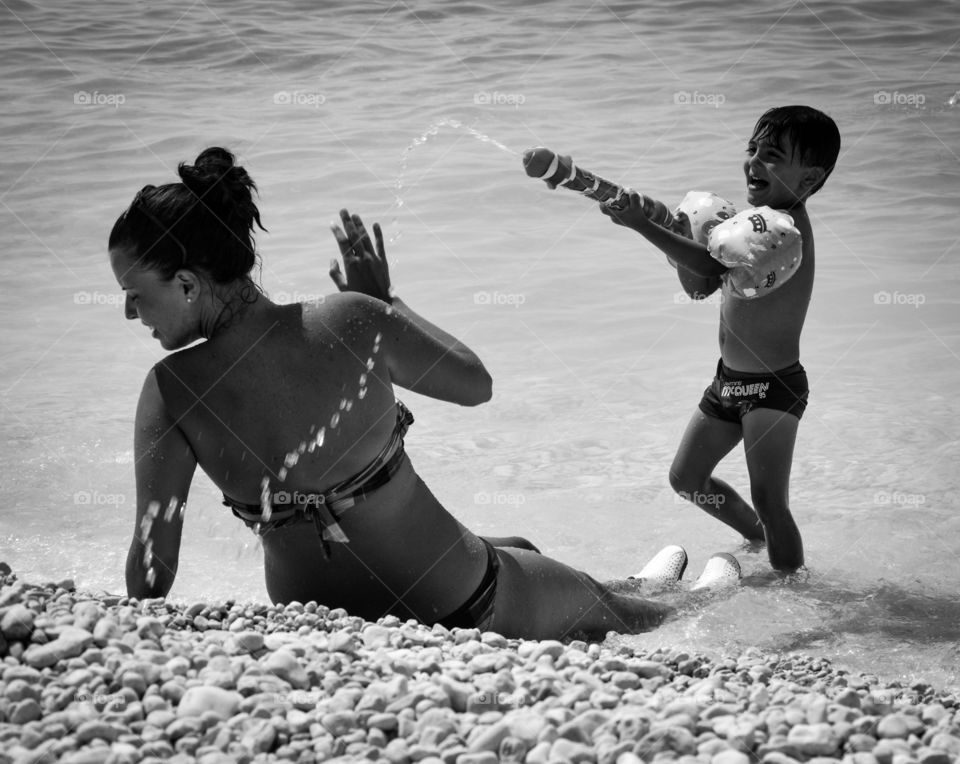 Boy splashing water on her mother with squirt gun