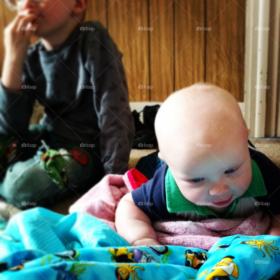 Baby examines blanket with rapt attention brother fazes out