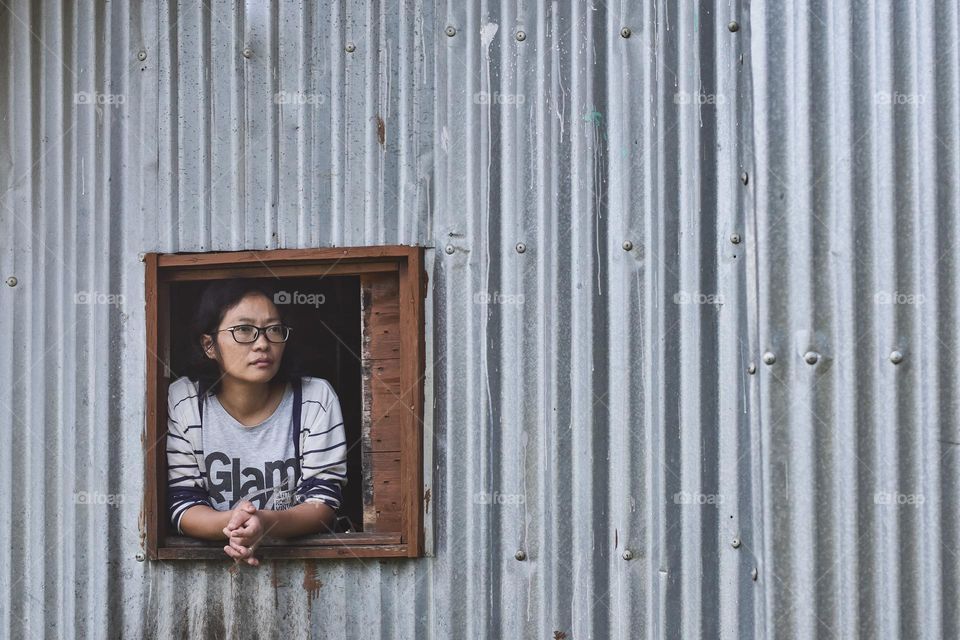 A woman looking out of a makeshift cabin window