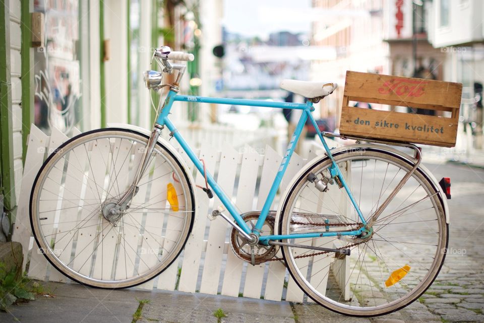 Bicycle parked on sidewalk against a white rail in Stavanger.