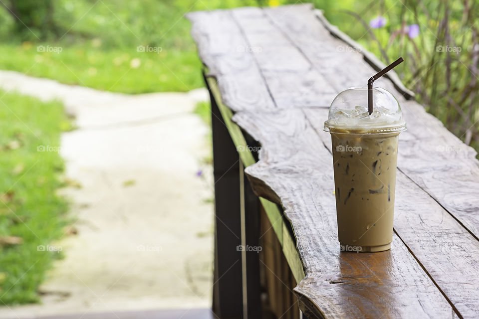 Iced coffee in glass on the table Background  Pennisetum pedicellatum and tree.