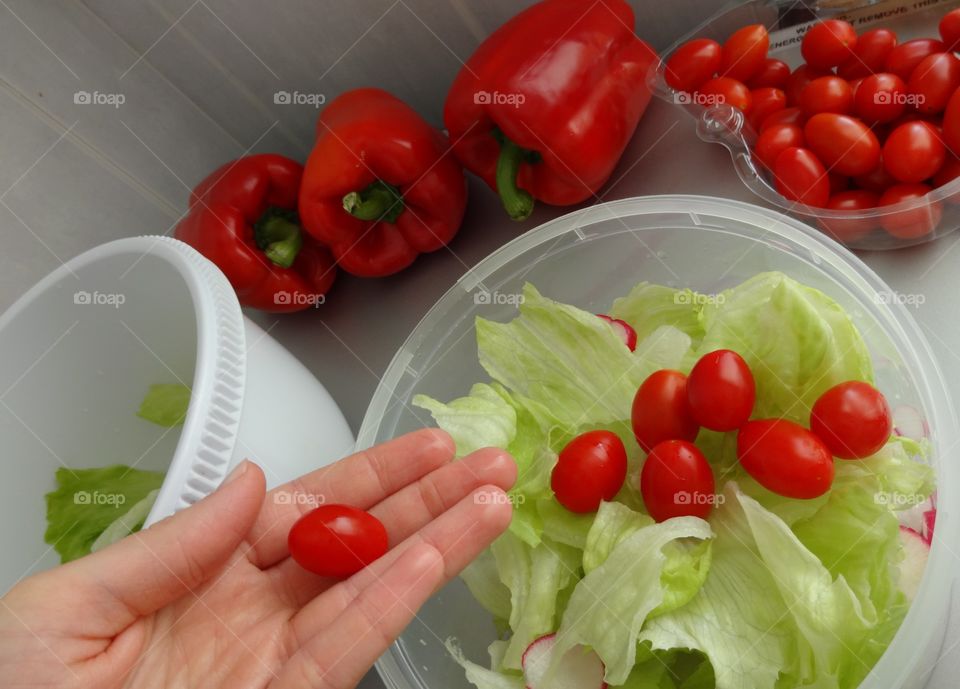 Person holding tomato against healthy vegetables