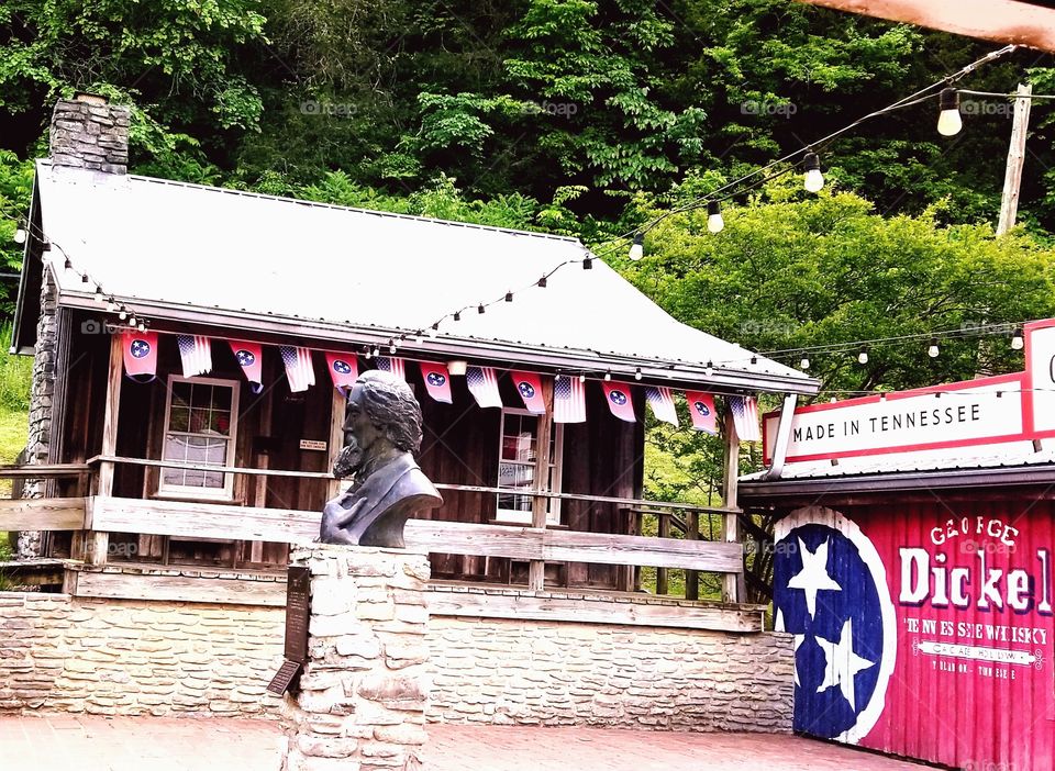 Iconic bronzed bust of famed whiskey maker, George Dickel at the American decorated front entrance of legendary Cascade Hollows with flags & stars of red, white, and blue. TN