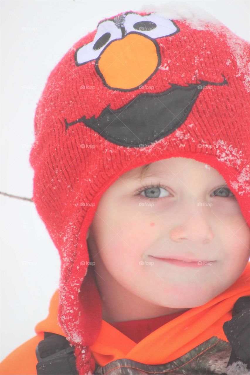 The sweetest little face of a five-year-old boy wearing his favorite Sesame Street Elmo toboggan out in the snow. 