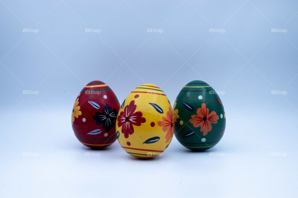 Three different wooden easter eggs with patterns  on moderately lit white background