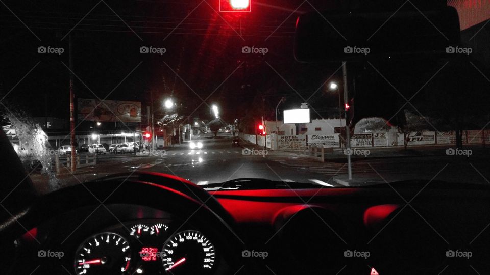 Do interior do veículo à noite no semáforo.