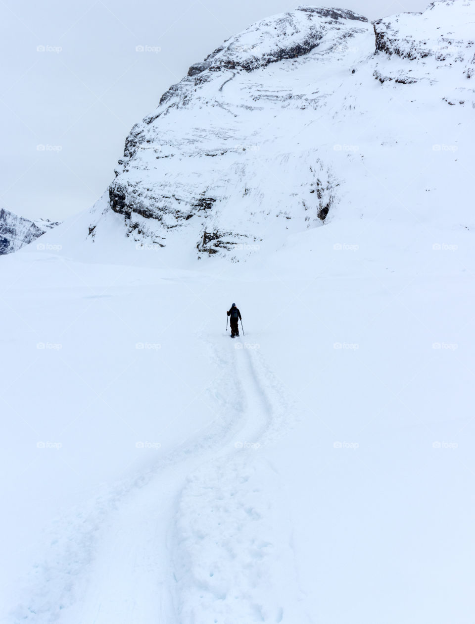 Snowshoeing through powder snow into the white winter landscape creating a path.
