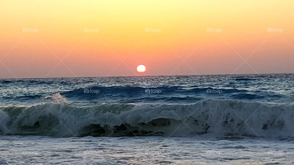 Sun goes under sea waves