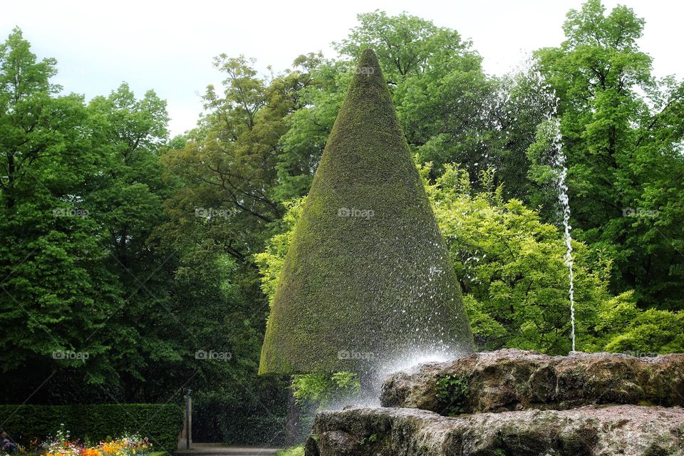 High jet of water from a fountain splashing on a rock in the city park