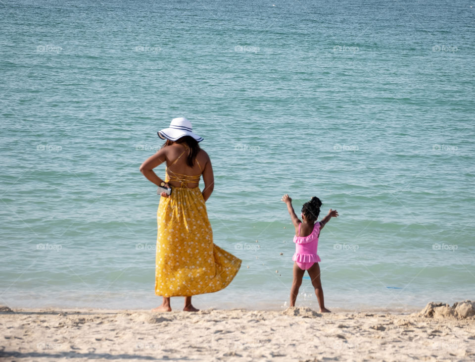 Mom and daugther in colorful swimming suit on the beach