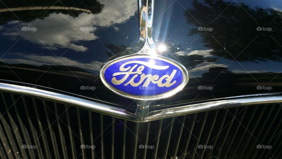 1932 ford hot rod radiator grill with Ford oval liquid black clouds sun reflecting