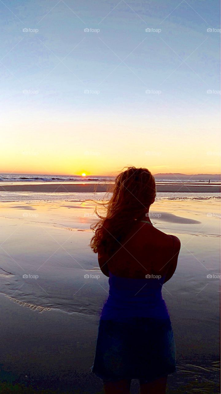 Girl watching sunset at the beach 