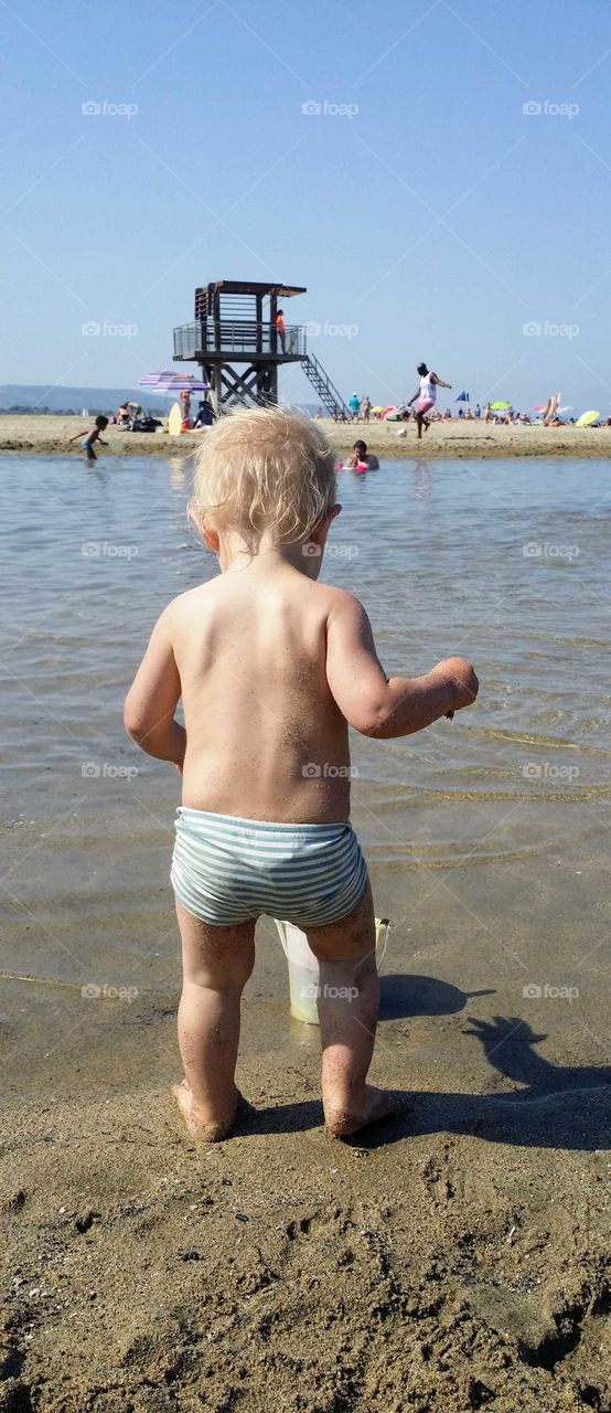 Little boy on beach with lifeguard tower in background