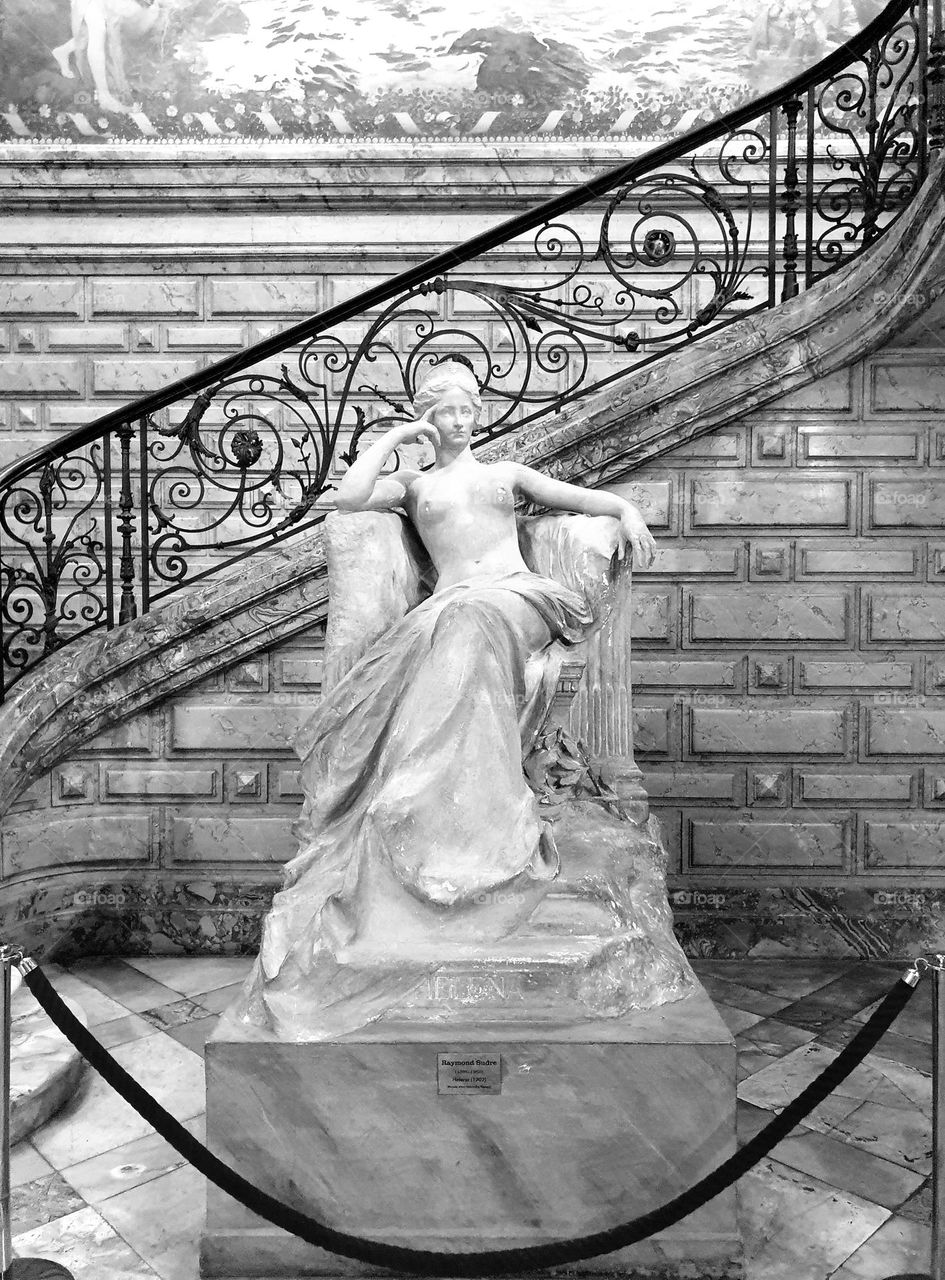 Black and white shot of Art Nouveau statue of Helena and cast iron staircase handrail in Hotel Pams in Perpignan