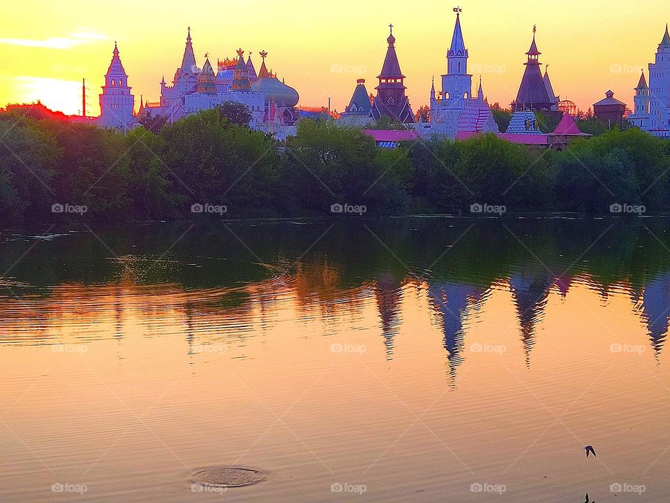 Sunset.  On the water of the river, reflections of the towers of domes and trees.  The domes of the towers at sunset were painted in different shades of purple.  Peace and tranquility of nature