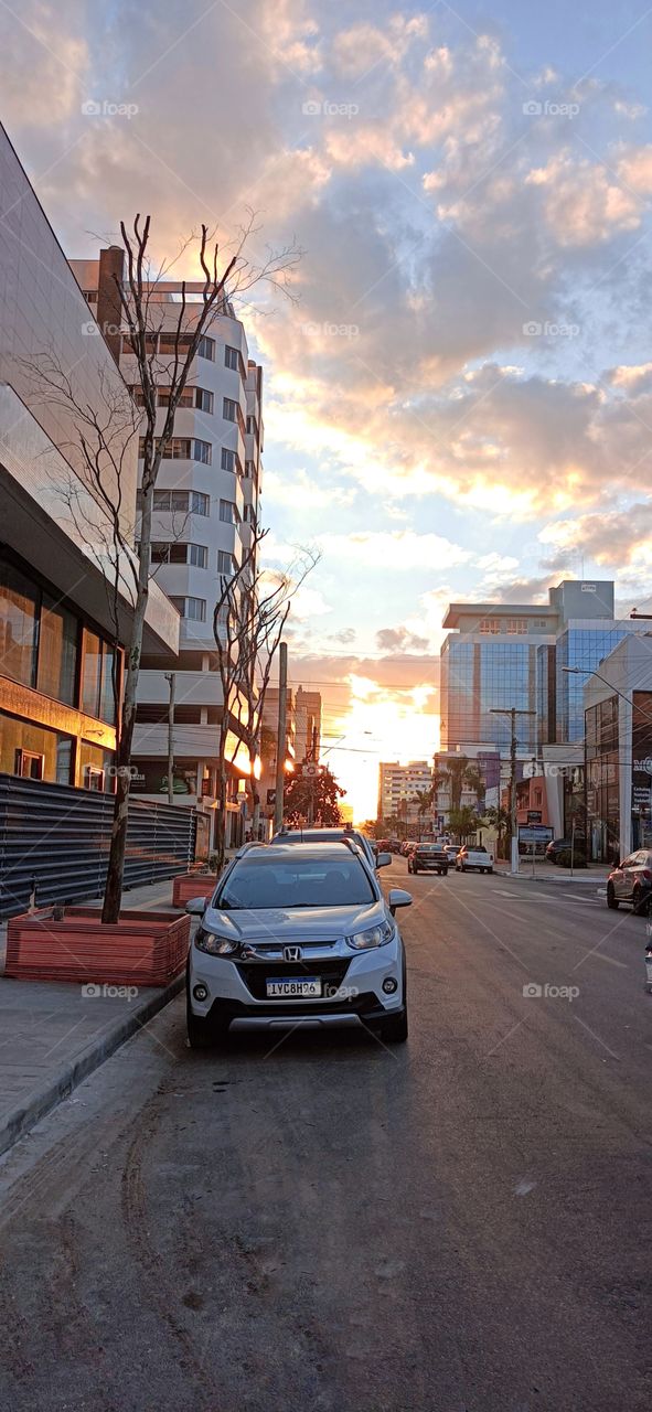 Streets, cars and buildings in the city at sunset