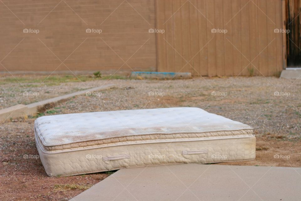 Old worn abandoned mattress in an empty lot.