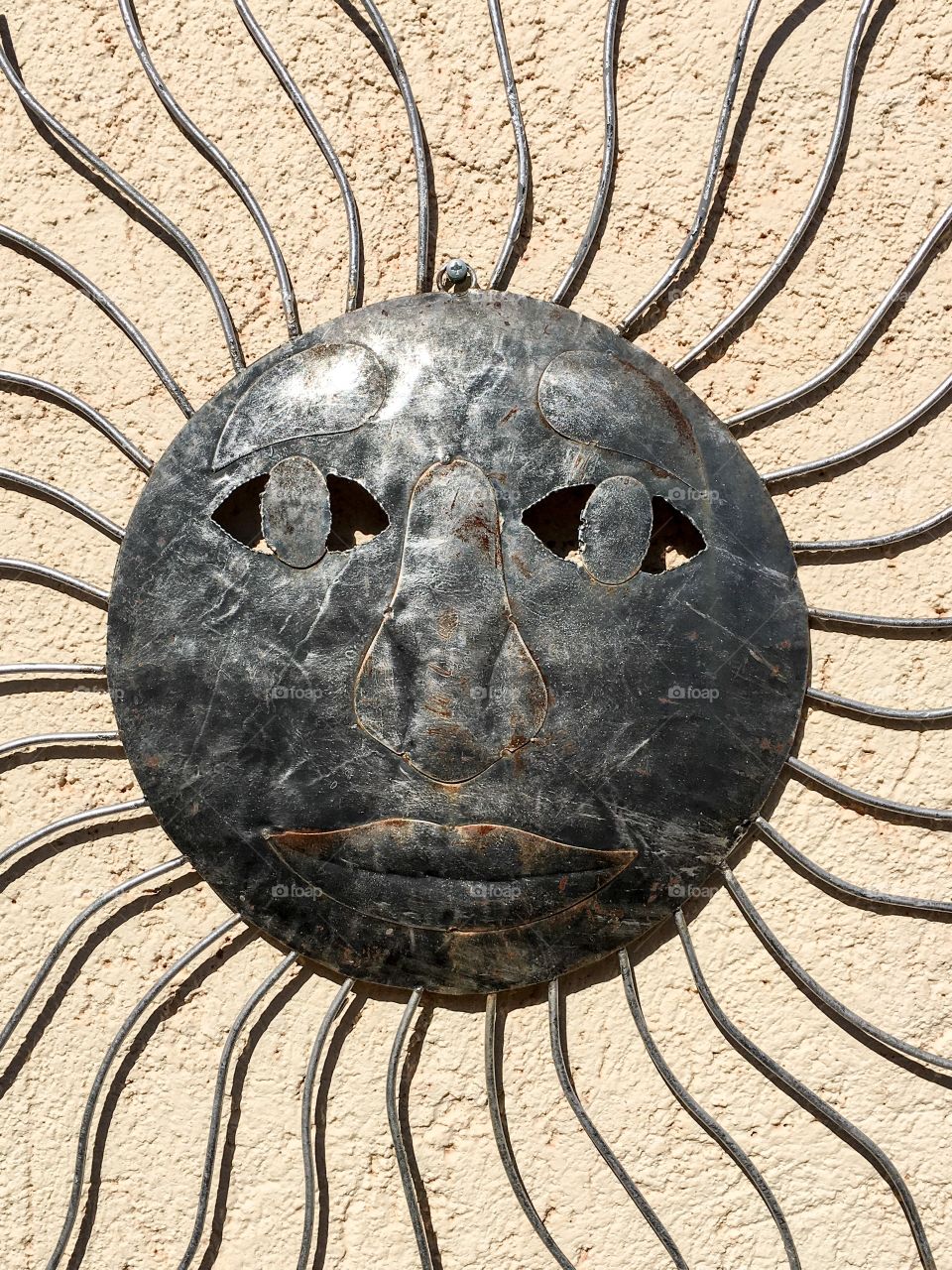 Grey tin art piece; sun with face and rays