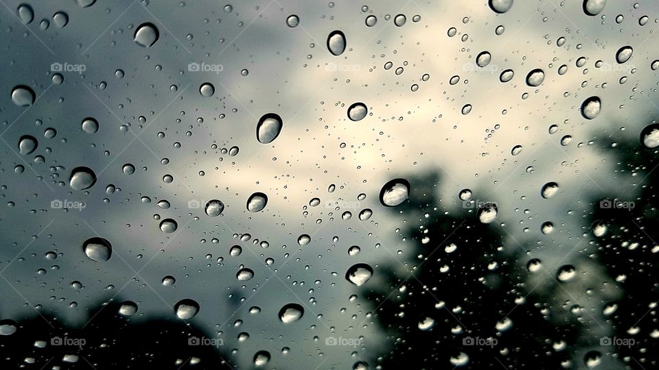 Raindrop on windshield of car with sky in background.