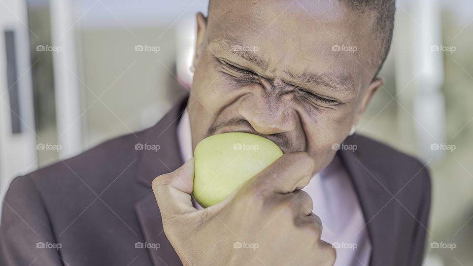 Afro American businessman eating green apple