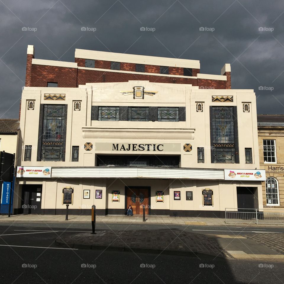 Storm Clouds ... sun lighting up the old majestic picture house with a contrasting black sky. I spotted a lonesome figure sitting on the steps ... I wonder who she is waiting for ?