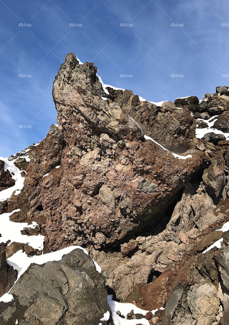 Jagged hardened lava rock with snow points into a beautiful blue sky on a winter day in Central Oregon. 