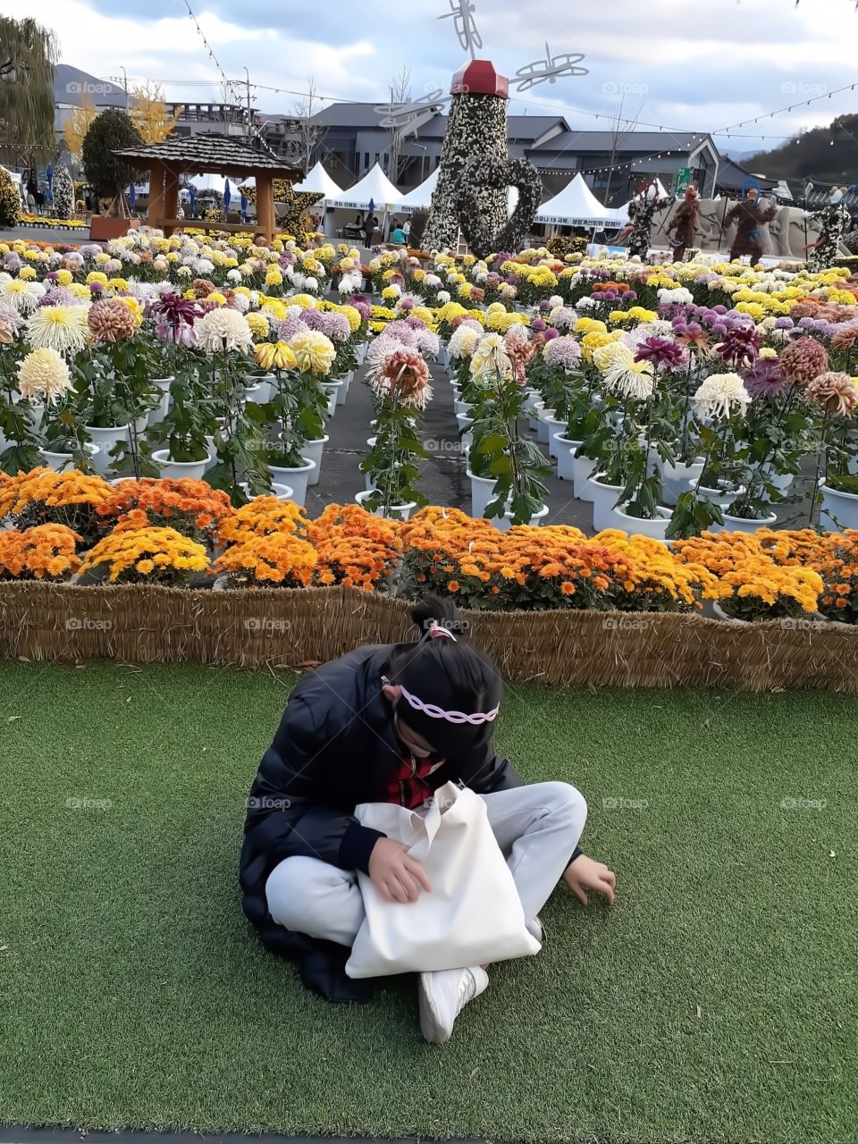 sitting on the grass with variety of flowers at the back.