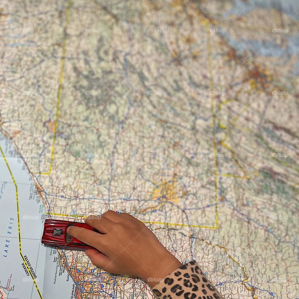 Planning a road trip with a toddler, driving cars on maps, hot wheels cars on maps, driving on roads on paper maps, planning a summer getaway