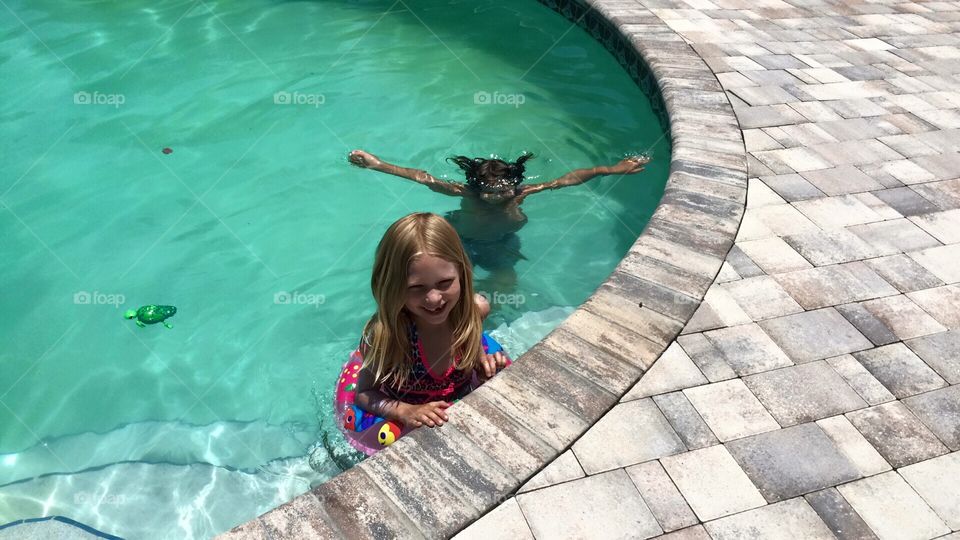 Kids swimming in the pool on a hot summer day