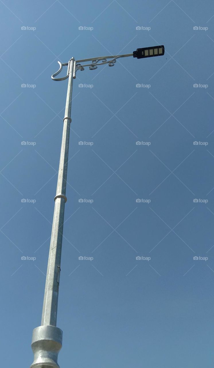 Street lighting poles, against a clear blue sky background