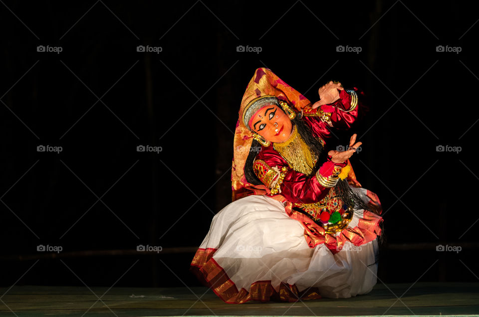 A artist performing a traditional south indian dance called Kathakali at night.
