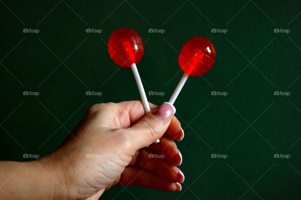 A hand holding red lollipops