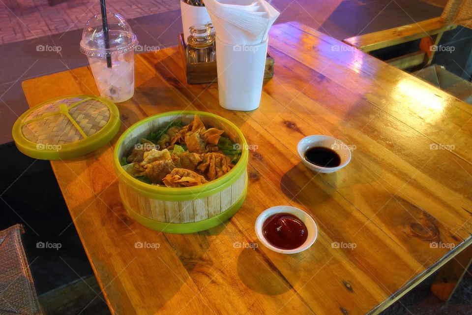 Asian dumplings fried in a bamboo basket with sauce