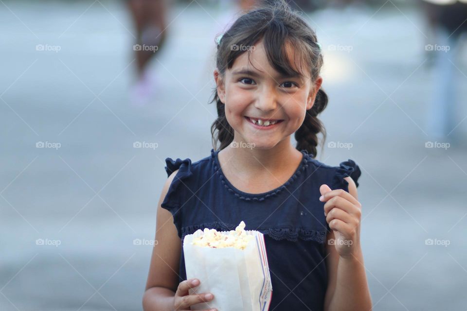 Cute happy little girl with popcorn