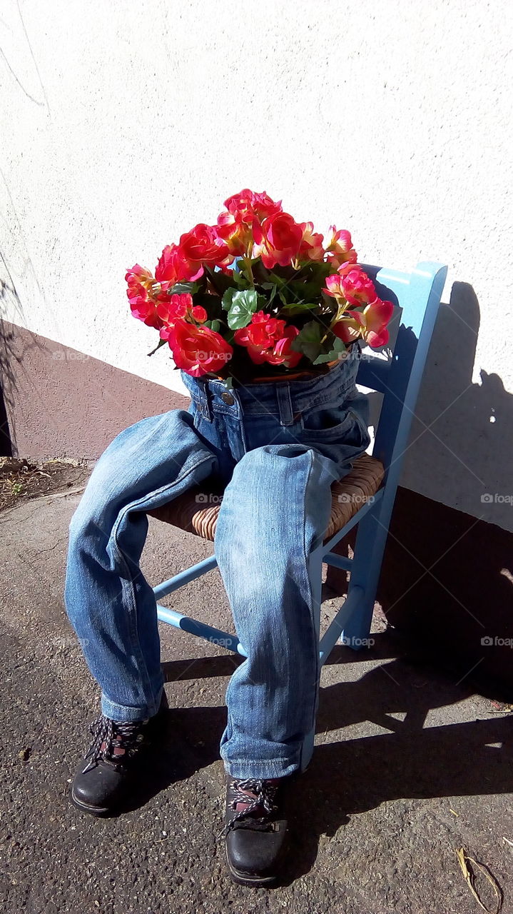 flower top on the chair of old jean and old shoes