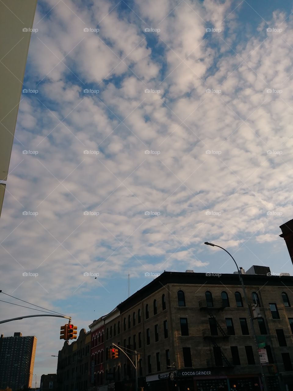 popcorn clouds over shadowed building day