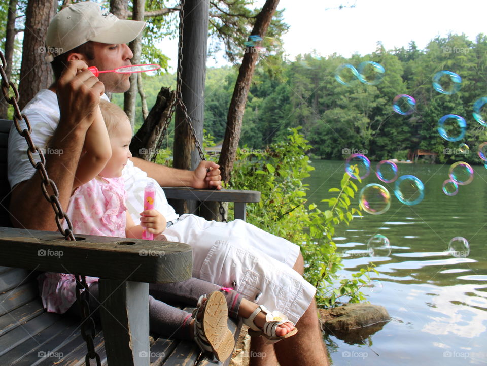 father daughter swinging and blowing bubbles