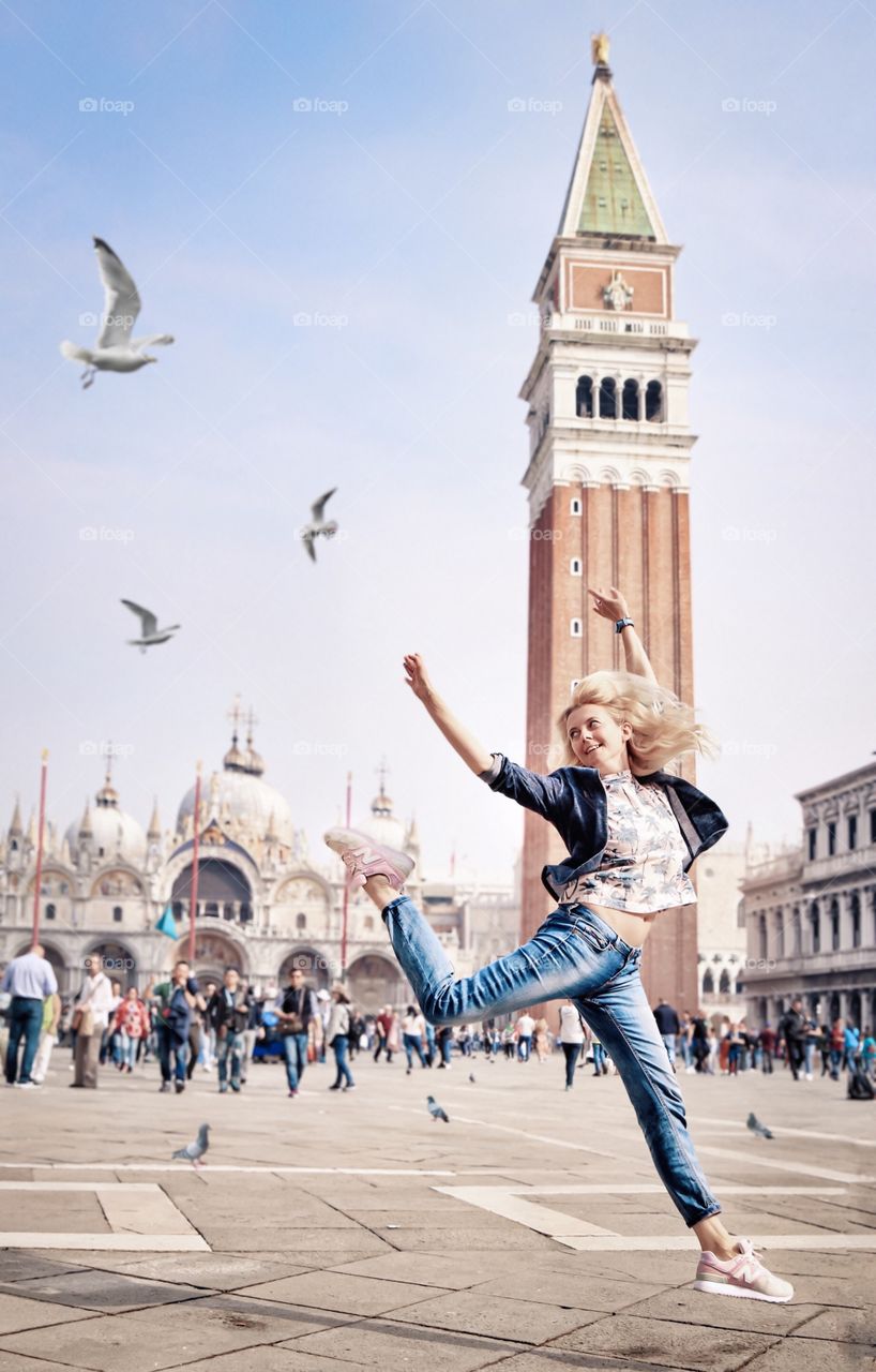 Happy blonde jumping in a square in Venice