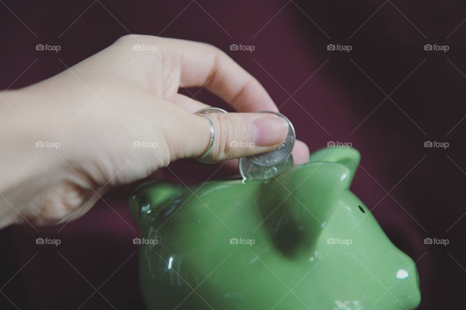 Close-up of a hand putting currency in piggy bank