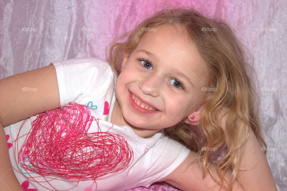 Pretty little five-year-old girl smiling for a Valentine picture.
